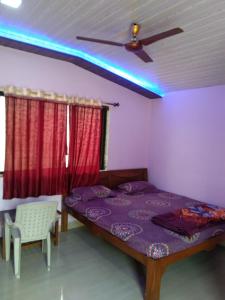 een slaapkamer met een bed en een plafondventilator bij Advait Holiday Home in Nagaon