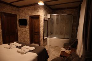 a bathroom with a shower and a bed and a tub at Calina Hotel in Uchisar