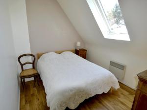 a bedroom with a white bed and a chair at Maison Arzon, 6 pièces, 11 personnes - FR-1-639-29 in Arzon