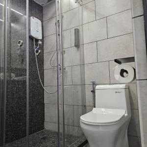a bathroom with a toilet and a glass shower at Pantai Inn Kota Kinabalu in Kota Kinabalu