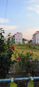 vistas a un patio con flores rojas y edificios en The Hideout Villa Raiwala Near Rishikesh, en Rāiwāla