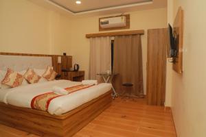 um quarto com uma cama e uma televisão num quarto em De Classico Hotel em Varanasi