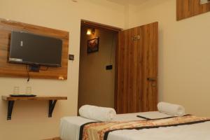 a room with two beds and a flat screen tv at De Classico Hotel in Varanasi