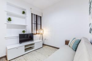 a living room with a white couch and a tv at apartamento reformado en el barrio de las letras in Madrid