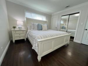 een witte slaapkamer met een groot bed en een spiegel bij Destination #04 in Anaheim