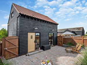 una pequeña casa negra con patio y valla en 1 Bed in Wix 92565, en Wix