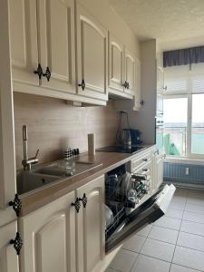 een keuken met witte kasten en een wastafel bij Blue Appartement in Sint-Niklaas