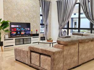 a living room with a large couch and a flat screen tv at 15-19Pax SemiD Near Highwy W/Pool Table&Karaoke in Ipoh
