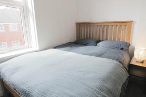 a bed with blue pillows in a bedroom with a window at Beautiful 1 Bedroom Central Flat in Leamington Spa