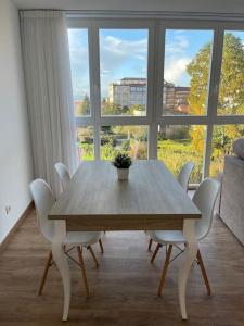 einen Esstisch mit weißen Stühlen und ein großes Fenster in der Unterkunft Apartamento céntrico con vistas in Santiago de Compostela