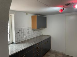 a kitchen with black cabinets and a white tile wall at Haus Dambacher - Arbeiter-Monteurzimmer in Nürtingen