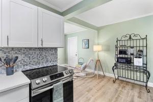 a kitchen with white cabinets and a stove top oven at Stylish Bungalow Steps to Beach! in St. Pete Beach