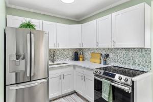 a kitchen with white cabinets and a stainless steel refrigerator at Stylish Bungalow Steps to Beach! in St. Pete Beach