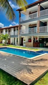 a villa with a swimming pool in front of a house at Pousada Villa Minduba in Japaratinga