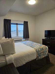 a bedroom with a bed and a window and a television at SureStay Studio by Best Western Hardisty in Hardisty