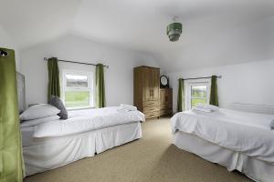 two beds in a white room with two windows at Rhea Holiday Home Bantry in Bantry