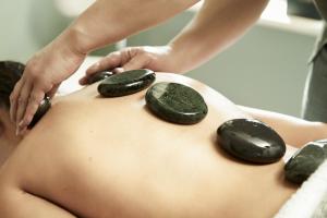 a woman getting a back massage with rocks on her back at Old Stable Mews Castle Leslie in Glaslough