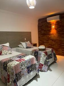 ein Schlafzimmer mit 2 Betten mit Steppdecken darauf in der Unterkunft Pousada Villa Minduba in Japaratinga