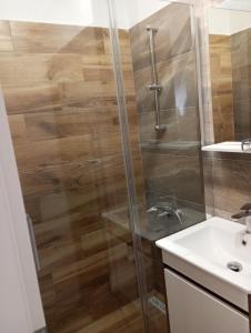 a shower with a glass door next to a sink at Apartmani Marina in Rab