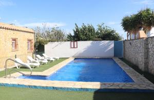 コニル・デ・ラ・フロンテーラにあるApartamento en Conil con piscinaのフェンスの横に椅子付きのスイミングプール