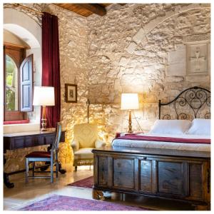 a bedroom with a bed and a desk in a stone wall at Eremo Della Giubiliana in Ragusa