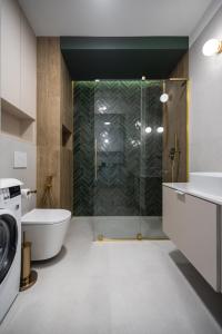 een badkamer met een douche en een wasmachine bij Krynica Apartamenty - Apartament z sypiąlnią i parkingiem Cicha 18 in Krynica Zdrój