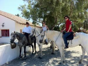 drie mensen die paardrijden voor een huis bij Cacharel in Saintes-Maries-de-la-Mer