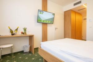 um quarto com uma cama e uma televisão na parede em Hotel B3 em Mauthausen
