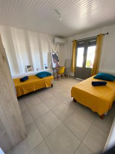 2 Betten in einem Zimmer mit gelber Bettwäsche in der Unterkunft Les Terrasses de Vinty 3 villas autour d'une piscine in Sainte-Rose