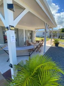 eine Veranda mit Stühlen, einem Tisch und Meerblick in der Unterkunft Les Terrasses de Vinty 3 villas autour d'une piscine in Sainte-Rose