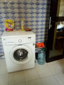 a washing machine in a room with a tile wall at Maison Manour, suite Maison Manour, chambre avec salle de bain privée in Mbour