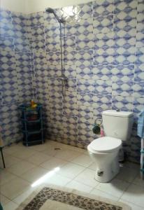 baño con aseo y azulejos azules y blancos en Maison Manour, suite Maison Manour, chambre avec salle de bain privée, en Mbour