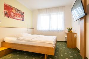 um quarto com uma cama e uma televisão de ecrã plano em Hotel B3 em Mauthausen