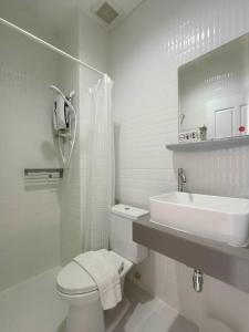 La salle de bains blanche est pourvue de toilettes et d'un lavabo. dans l'établissement The Guest Chang Moi Hotel, à Chiang Mai