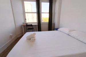 ein Schlafzimmer mit einem weißen Bett und einem Handtuch darauf in der Unterkunft VibesCoruña- Ferrocarril 2 in A Coruña