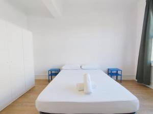 ein weißes Bett in einem Zimmer mit blauen Stühlen in der Unterkunft VibesCoruña- Ferrocarril 2 in A Coruña