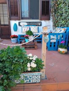 un porche con bancos azules, flores y plantas en VILLA CORALLINA en San Vito lo Capo