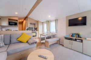 a living room with a couch and a kitchen at 30 Bayside Cove Pevensey Bay Holiday Park in Pevensey