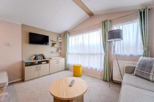 a living room with a couch and a table at 30 Bayside Cove Pevensey Bay Holiday Park in Pevensey
