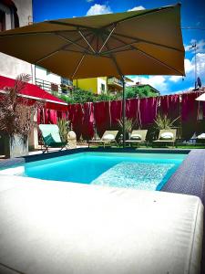 uma piscina com um guarda-sol e cadeiras e uma mesa em WELCOME TRAVELLER FRIDA'S ROOMs em Caprino Veronese