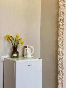 einen weißen Kühlschrank mit einer Blumenvase darüber in der Unterkunft Moedani-Very Center Apartments in Kutaisi in Kutaissi