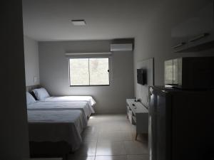 a bedroom with a bed and a window and a television at Porto Residence in Vitória da Conquista
