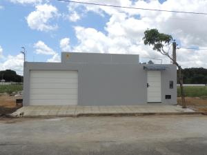a white garage with two doors and a tree at Porto Residence in Vitória da Conquista