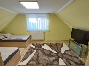a small room with two beds and a television at Édenkert Apartmanház in Kisvárda