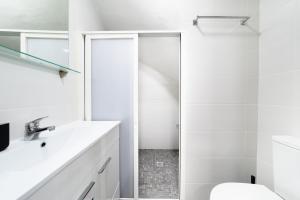 a white bathroom with a shower and a toilet at Casa da Carochinha in Nazaré +7 photos