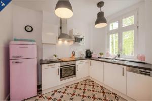 ヘリングスドルフにあるHohe Buchen Apartment 2のキッチン(白いキャビネット、ピンクの冷蔵庫付)