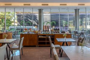 um restaurante com mesas, cadeiras e janelas em Tryp by Wyndham Asuncion em Assunção