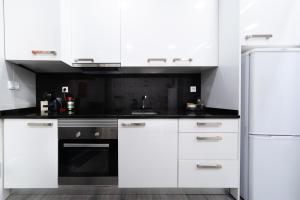 a white kitchen with white cabinets and a refrigerator at Casa da Carochinha in Nazaré