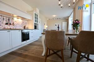 a kitchen with white cabinets and a table and chairs at Alte Feuerwache Ferienwohnung 1 in Wangerooge