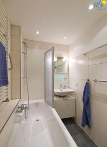 a white bathroom with a tub and a sink at Haus Solaris - Ferienwohnung Westblick in Wangerooge